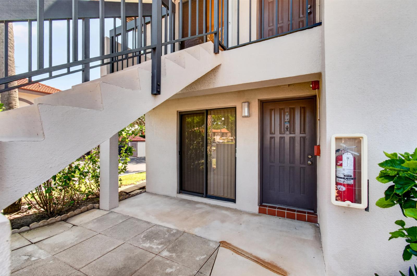 An exterior view of a ground-floor apartment entrance with a staircase and fire extinguisher — 351 Club Circle # 101, Boca Raton FL 33487, BOCA RATON, FL
