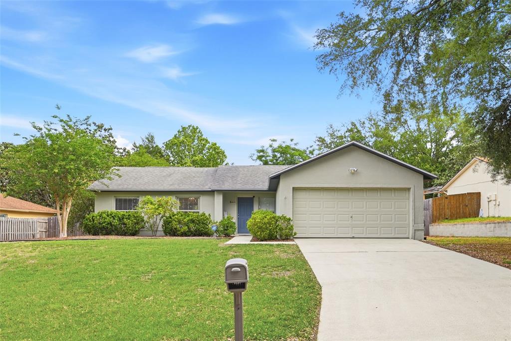 A single-story house with a gray exterior, a two-car garage, and a front lawn — 10618 LAKE RALPH DRIVE, CLERMONT, FL