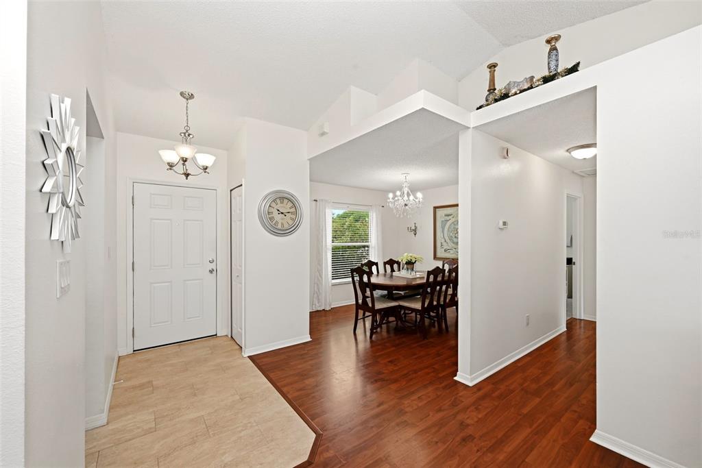 An entryway with light tile flooring leads to a dining room featuring dark wood floors — 10618 LAKE RALPH DRIVE, CLERMONT, FL