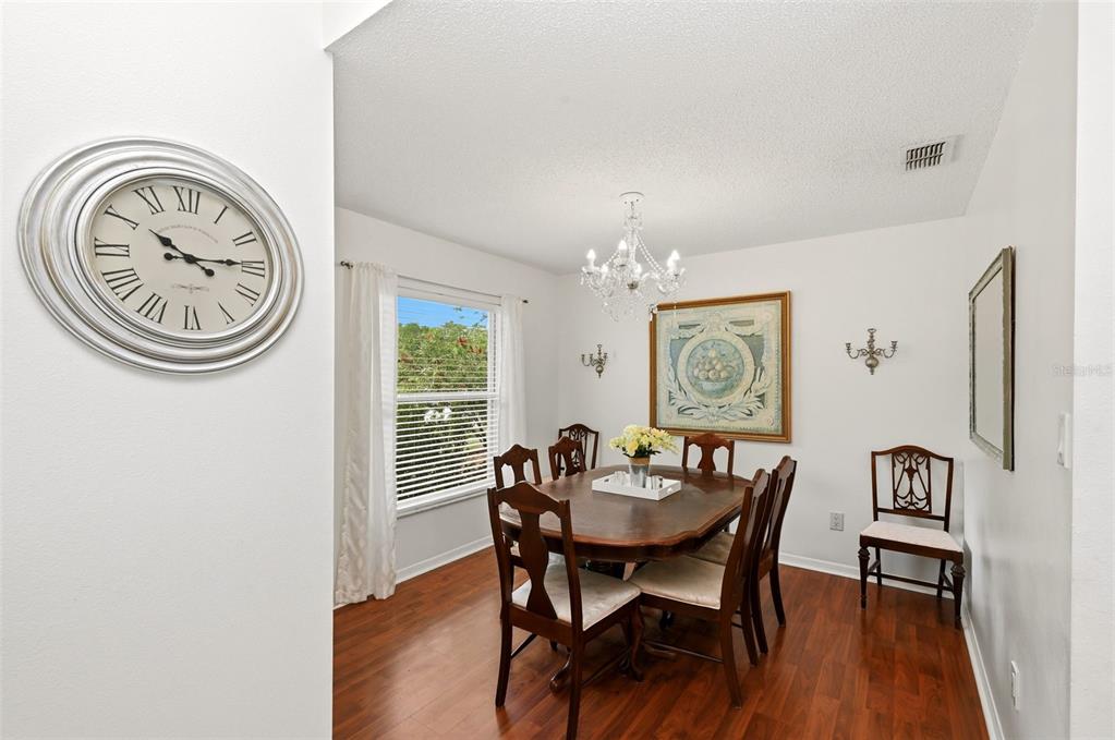 A dining room features a wooden table, chairs, a chandelier, and a large wall clock — 10618 LAKE RALPH DRIVE, CLERMONT, FL