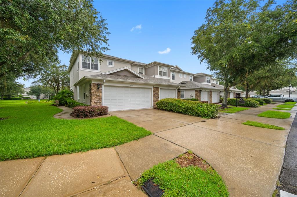 A two-story townhouse with a two-car garage, stone accents, and a concrete driveway — 10302 STONE MOSS AVENUE, TAMPA, FL