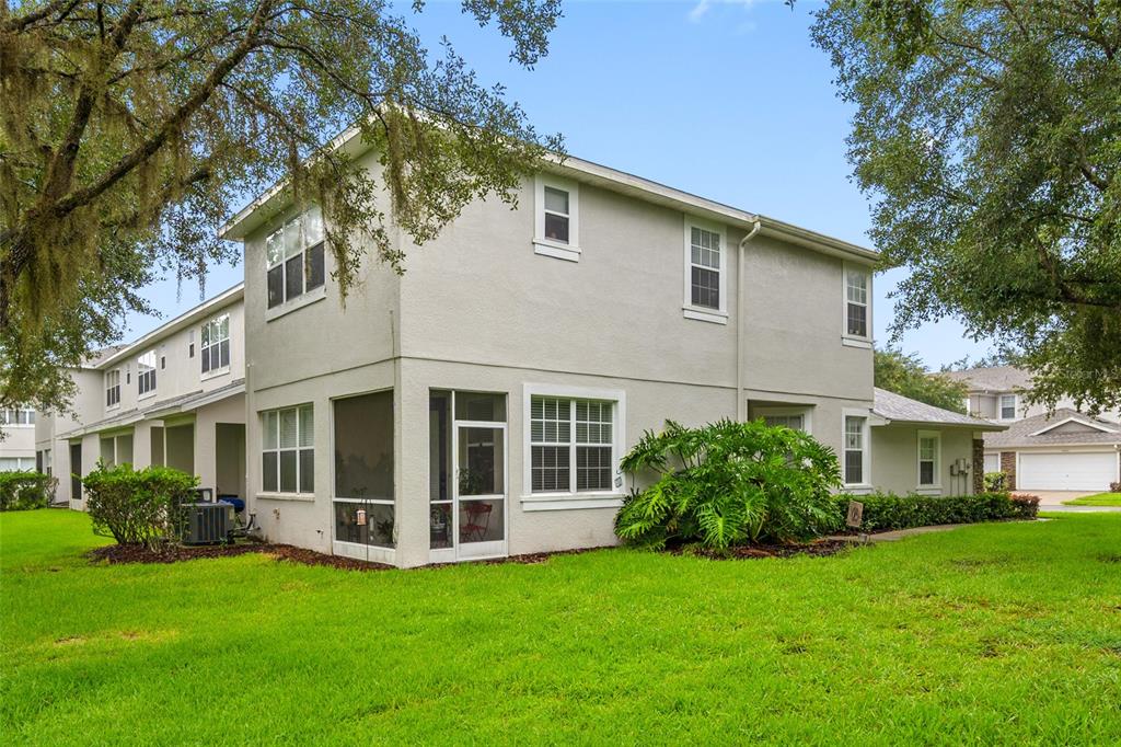 A two-story beige townhouse with a screened-in porch and a green lawn — 10302 STONE MOSS AVENUE, TAMPA, FL