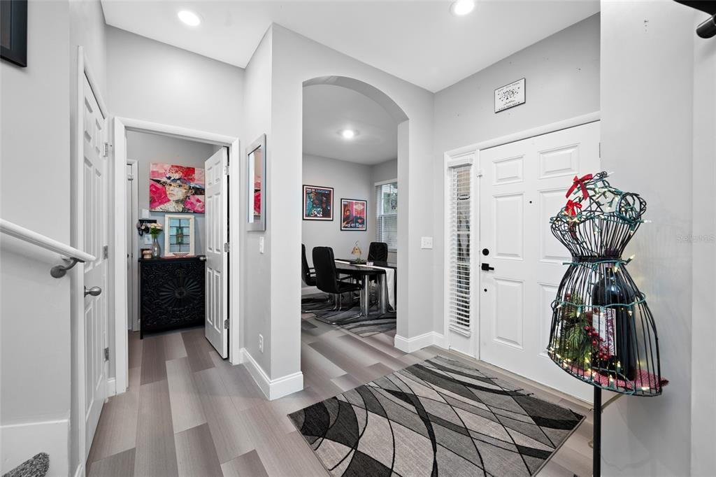 An entryway features light gray wood-look flooring, an arched doorway, and a white front door — 10302 STONE MOSS AVENUE, TAMPA, FL