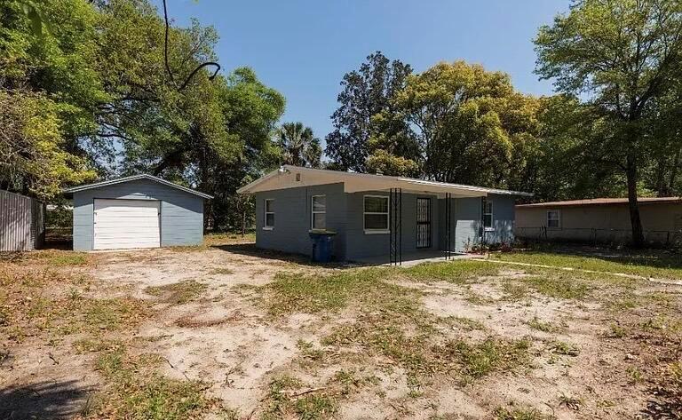 A blue single-story house with a detached garage sits on a sandy, tree-lined lot — 2513 Spirea Street, Jacksonville FL 32209, JACKSONVILLE, FL