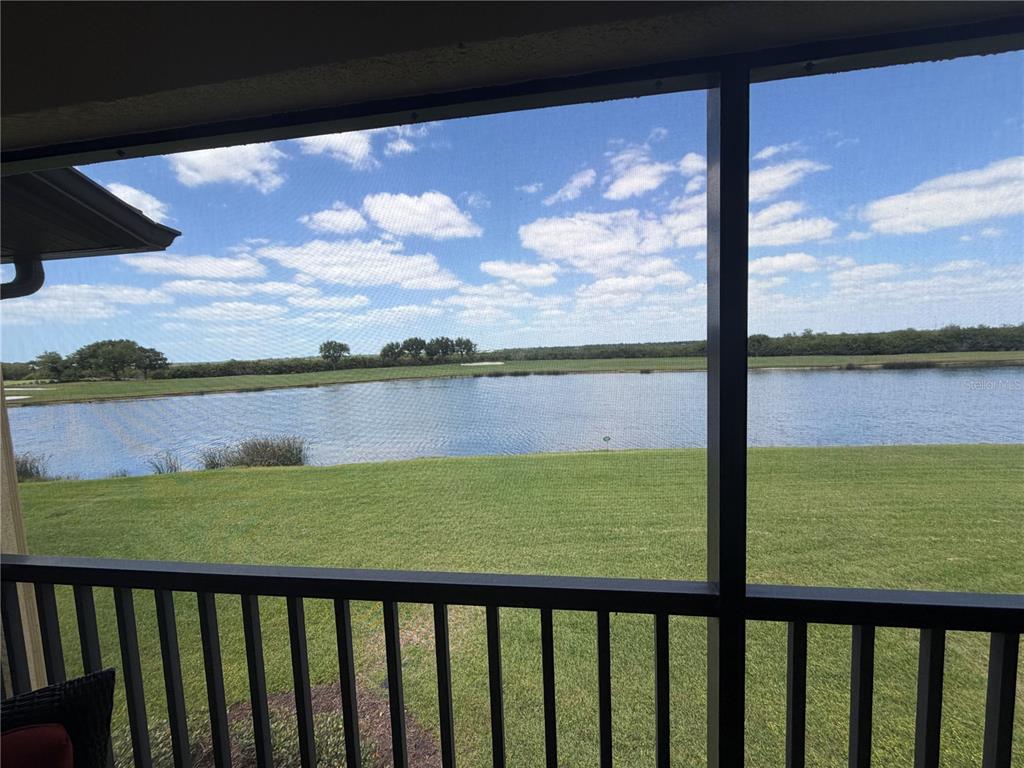 A screened-in porch overlooks a grassy lawn, a pond, and a distant treeline — 7225 RIVER HAMMOCK DRIVE UNIT 202, BRADENTON, FL