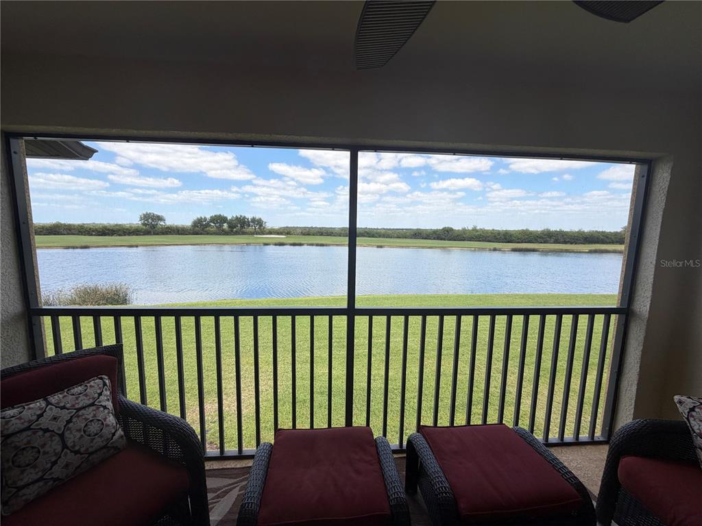 A screened-in patio overlooks a lake and a golf course — 7225 RIVER HAMMOCK DRIVE UNIT 202, BRADENTON, FL
