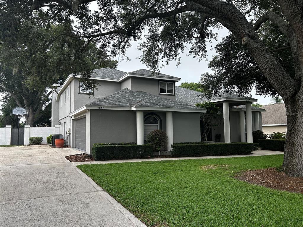 A two-story gray house with a multi-gabled roof, white columns, and a concrete driveway — 936 HAMILTON PLACE DRIVE, LAKELAND, FL