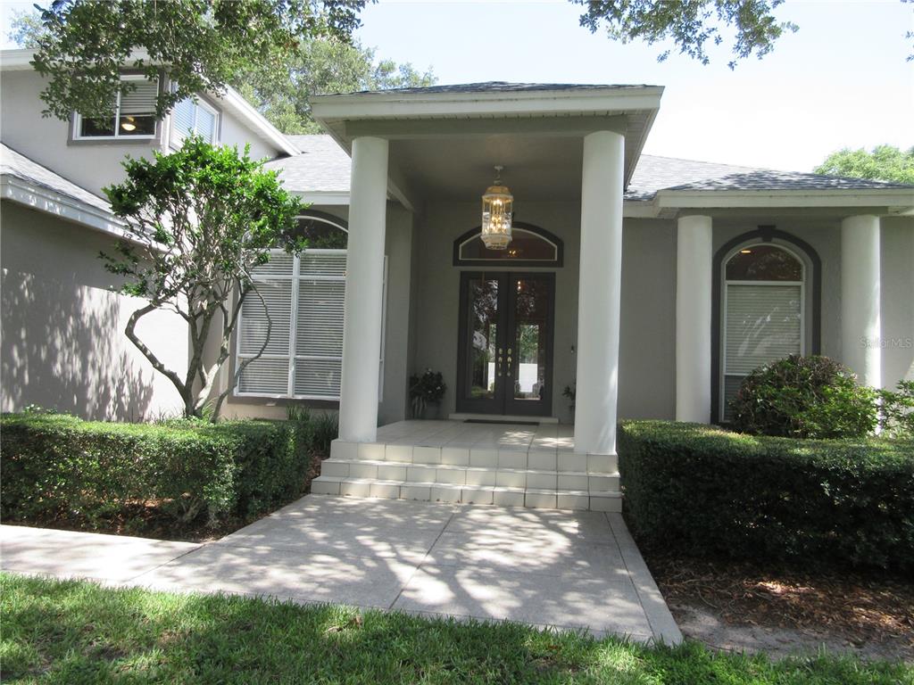 The exterior of a house features a covered entryway with white columns and double doors — 936 HAMILTON PLACE DRIVE, LAKELAND, FL
