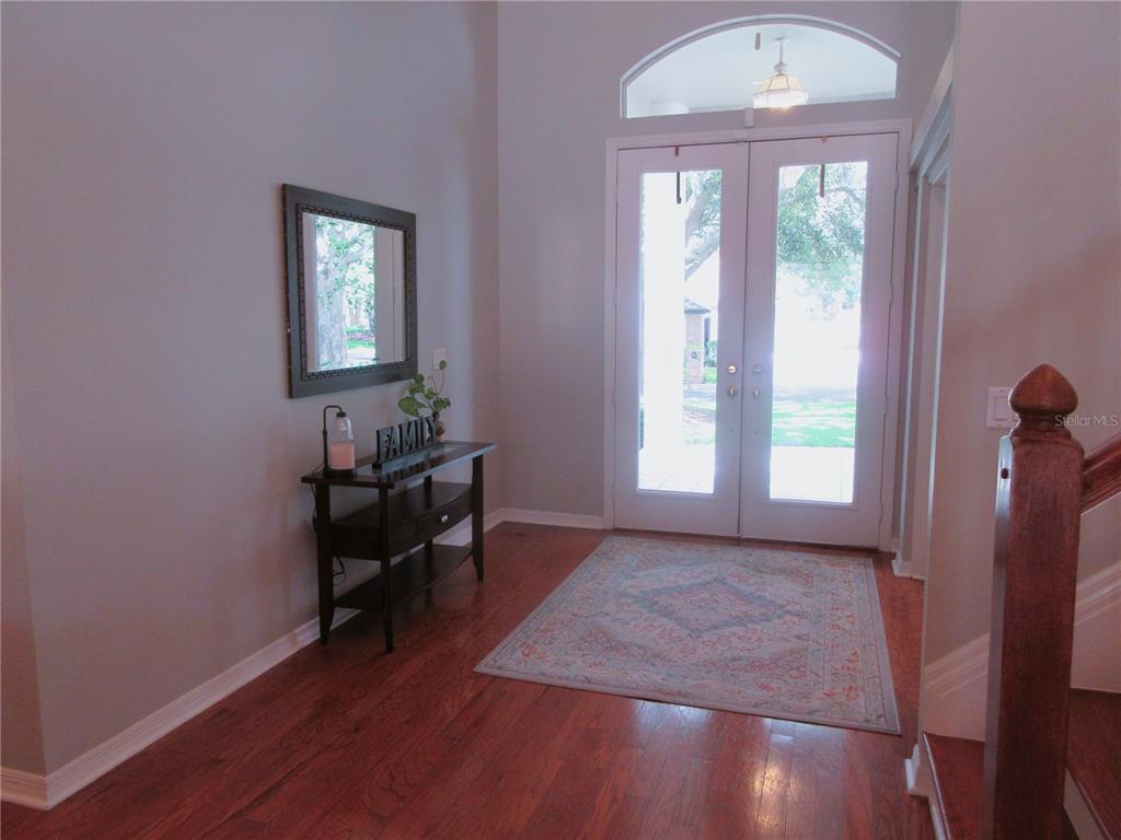 A foyer features hardwood floors, a console table with a mirror, and double glass doors — 936 HAMILTON PLACE DRIVE, LAKELAND, FL