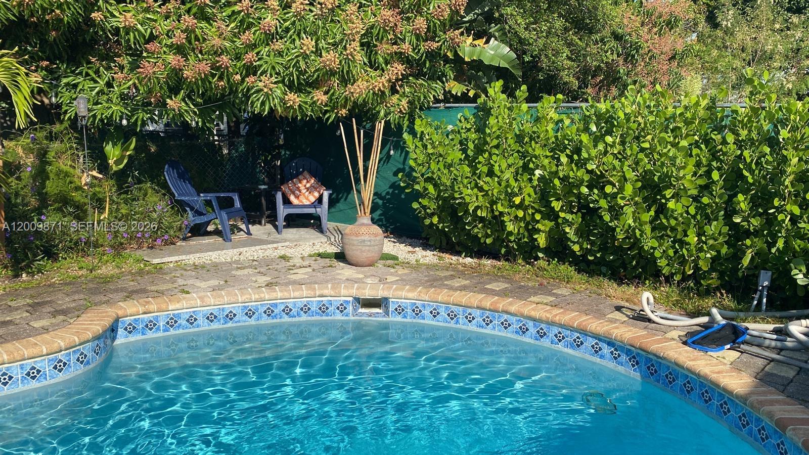 A swimming pool sits in front of a patio area with two chairs and landscaping — 220 SW 3rd Ave # 0, Hallandale Beach FL 33009, HALLANDALE BEACH, FL