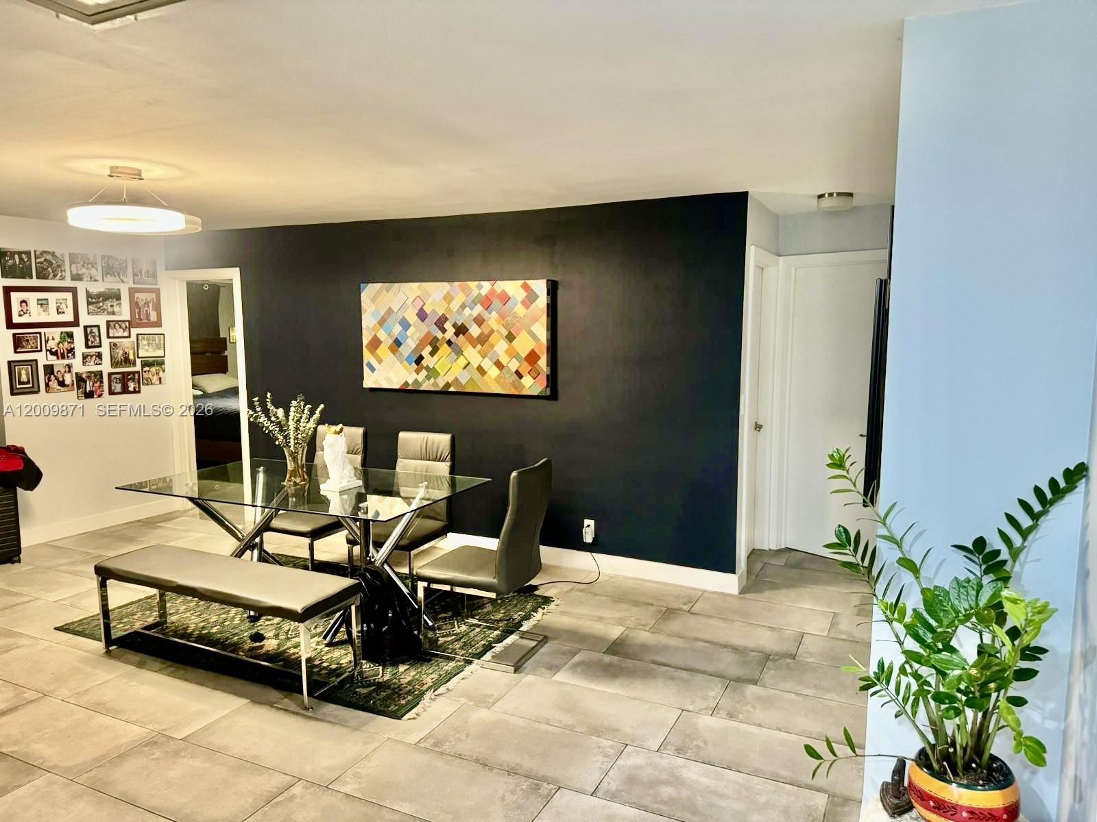 A dining room features a glass table, gray chairs, a bench, and a dark accent wall — 220 SW 3rd Ave # 0, Hallandale Beach FL 33009, HALLANDALE BEACH, FL
