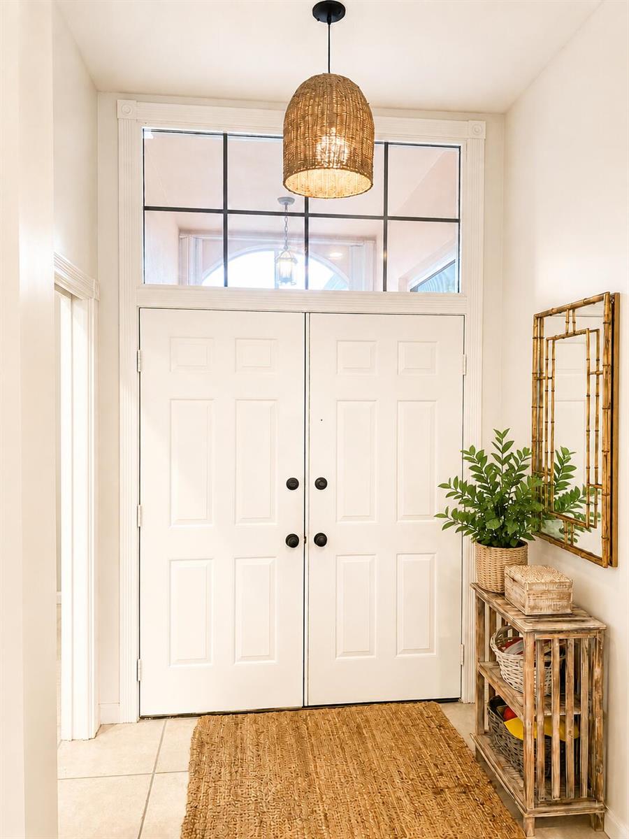 A bright entryway features double white doors, a transom window, a woven pendant light, and furniture — 7529 SE Bay Cedar Circle, Hobe Sound FL 33455, HOBE SOUND, FL