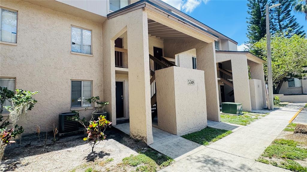 Exterior view of a two-story tan stucco apartment building with an outdoor staircase — 5508 POKEWEED COURT UNIT 146, TAMPA, FL