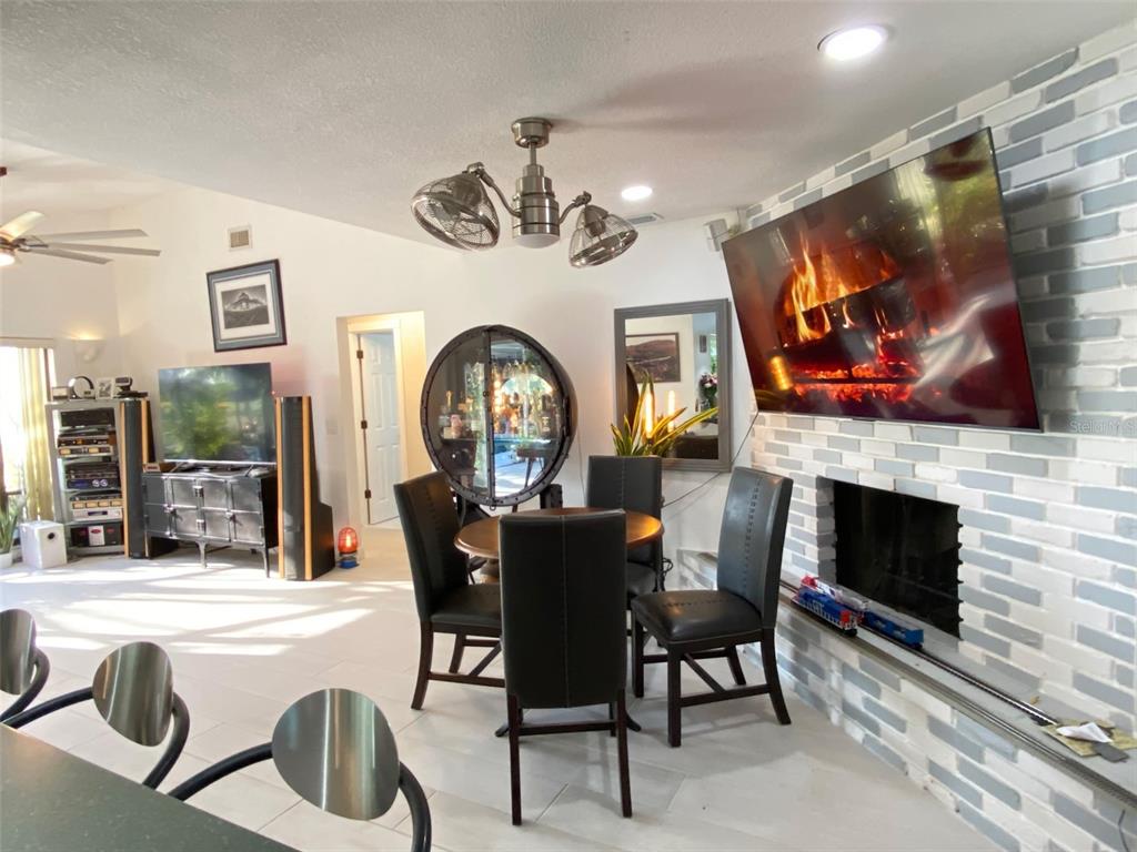 A dining area with a round table, black chairs, a fireplace, and a wall-mounted television — 4076 SOUTHWELL WAY, SARASOTA, FL