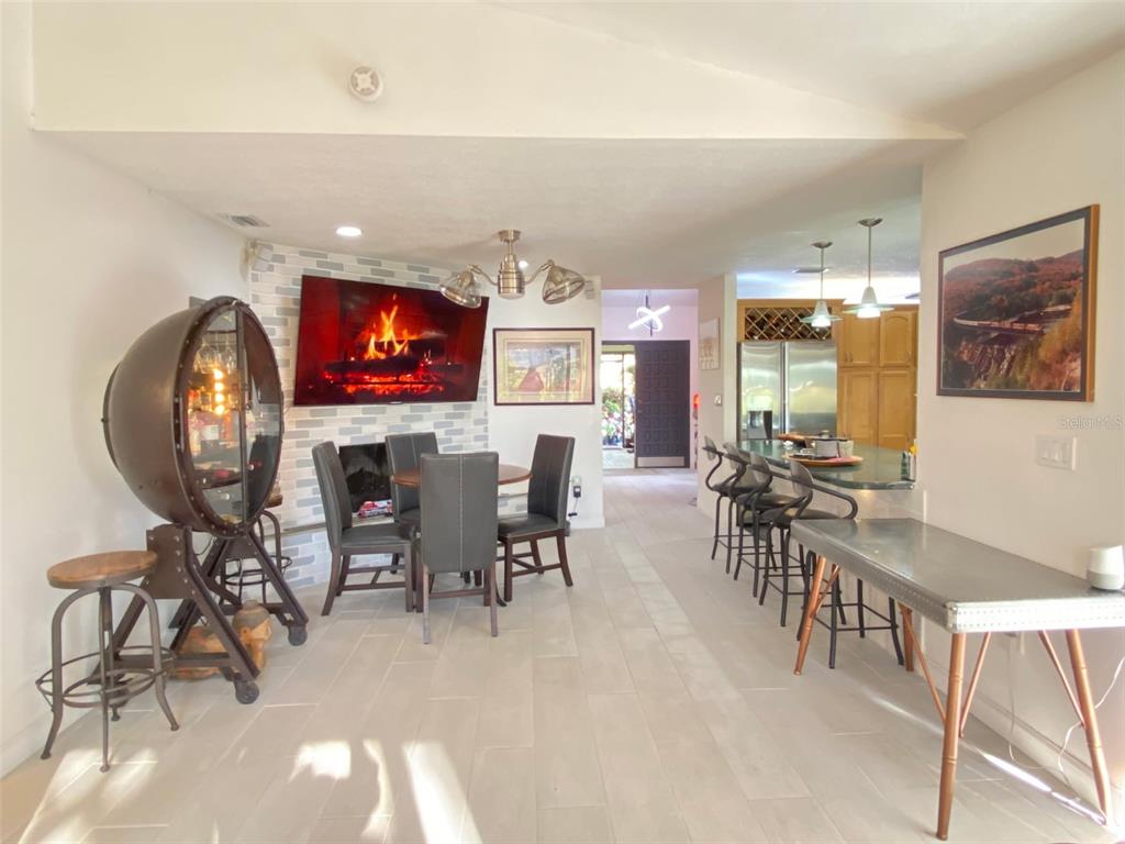 A dining area with a fireplace wall and a kitchen island with bar stools — 4076 SOUTHWELL WAY, SARASOTA, FL