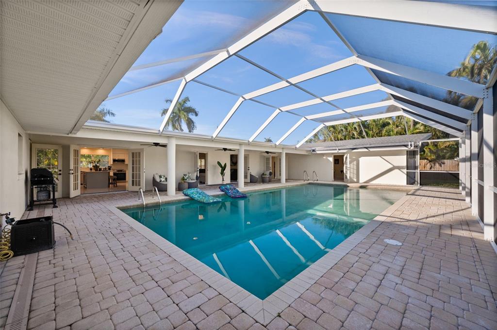 A screened-in swimming pool with a brick paver deck and a view of the house — 625 W OLYMPIA AVENUE, PUNTA GORDA, FL