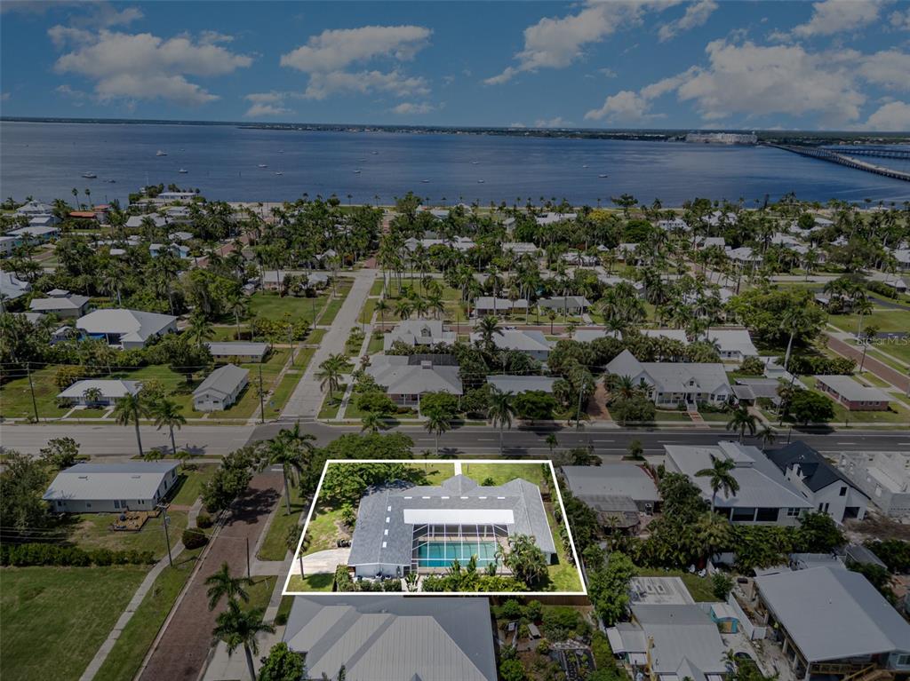 An aerial view shows a house with a screened-in pool located near a large body of water — 625 W OLYMPIA AVENUE, PUNTA GORDA, FL