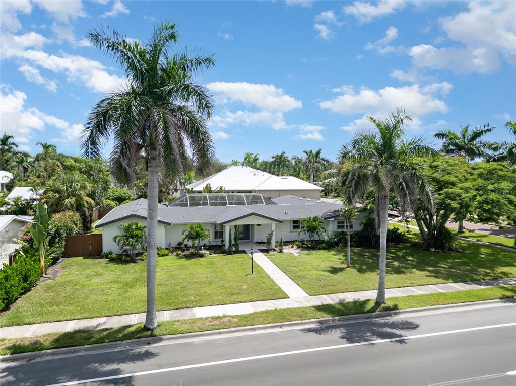 A single-story white house with a screened-in roof section sits behind two tall palm trees — 625 W OLYMPIA AVENUE, PUNTA GORDA, FL