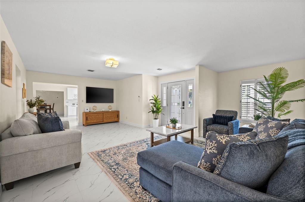 A living room features white marble-look tile floors, a blue sectional, and a television console — 625 W OLYMPIA AVENUE, PUNTA GORDA, FL
