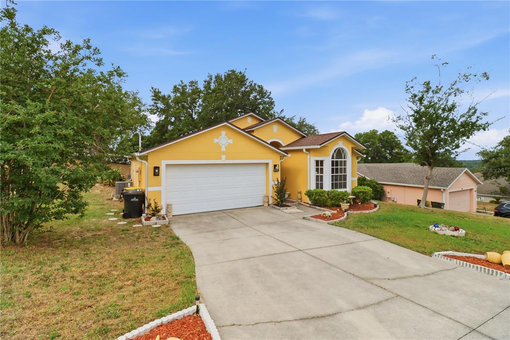 A yellow single-story house with a two-car garage and a concrete driveway — 1514 MUIR CIRCLE, CLERMONT, FL