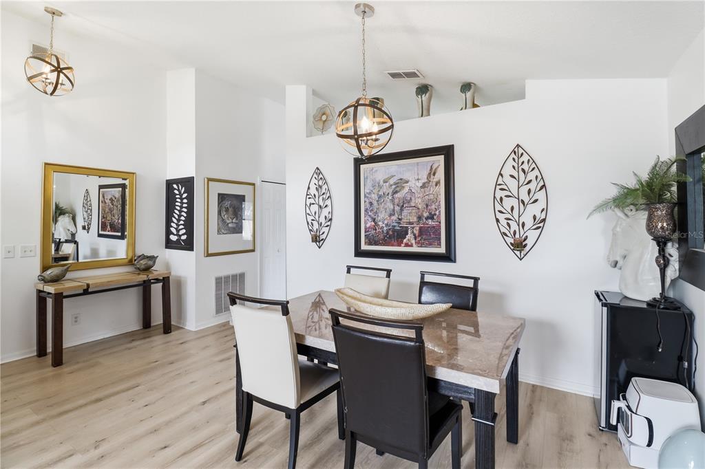 A dining room features a marble-topped table, modern chairs, globe pendant lights, and wall art — 1514 MUIR CIRCLE, CLERMONT, FL