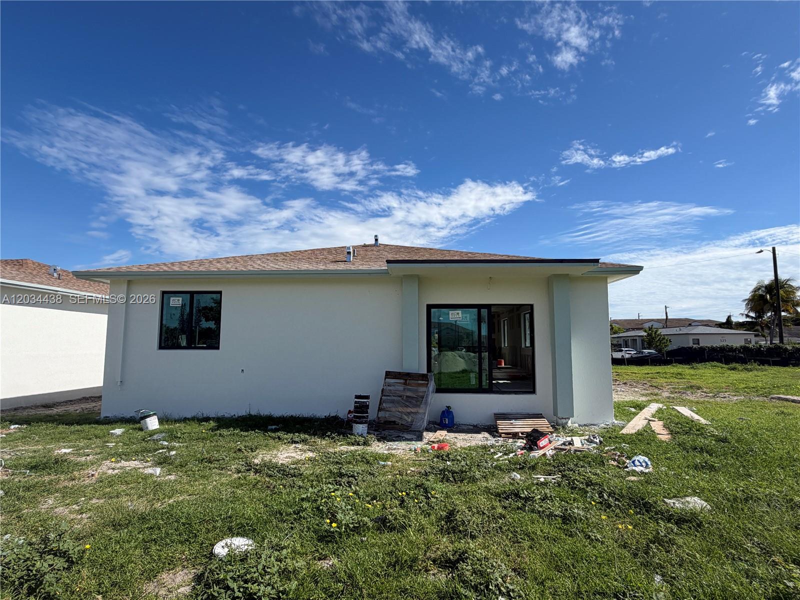 The exterior rear view of a single-story house shows a yard with construction debris — 336 NW 11th St, Pompano Beach FL 33060, POMPANO BEACH, FL