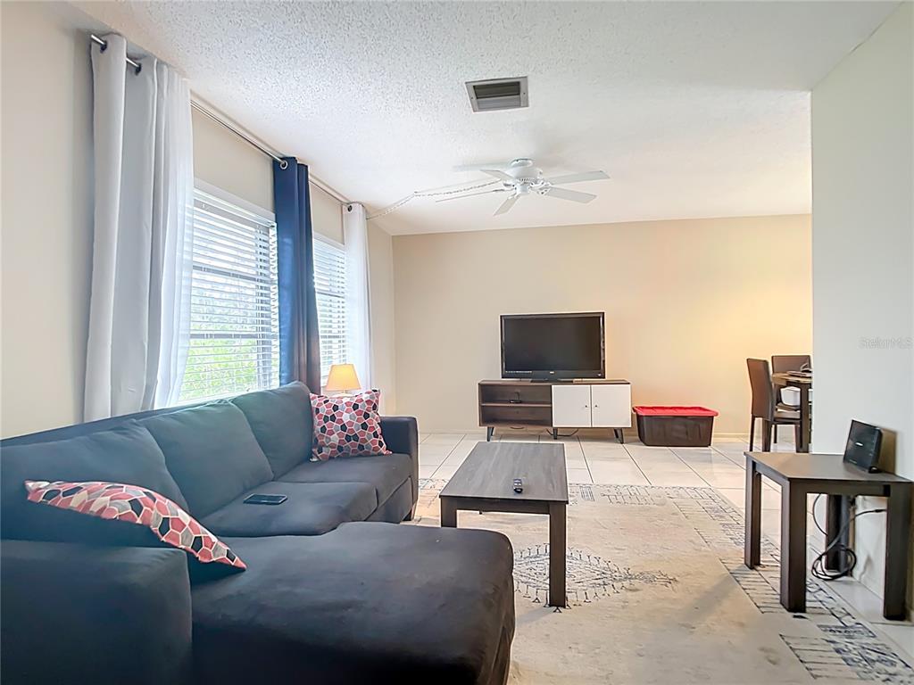 A living room features a dark sectional sofa, a coffee table, and a television console — 5964 DIANA ROAD, VENICE, FL