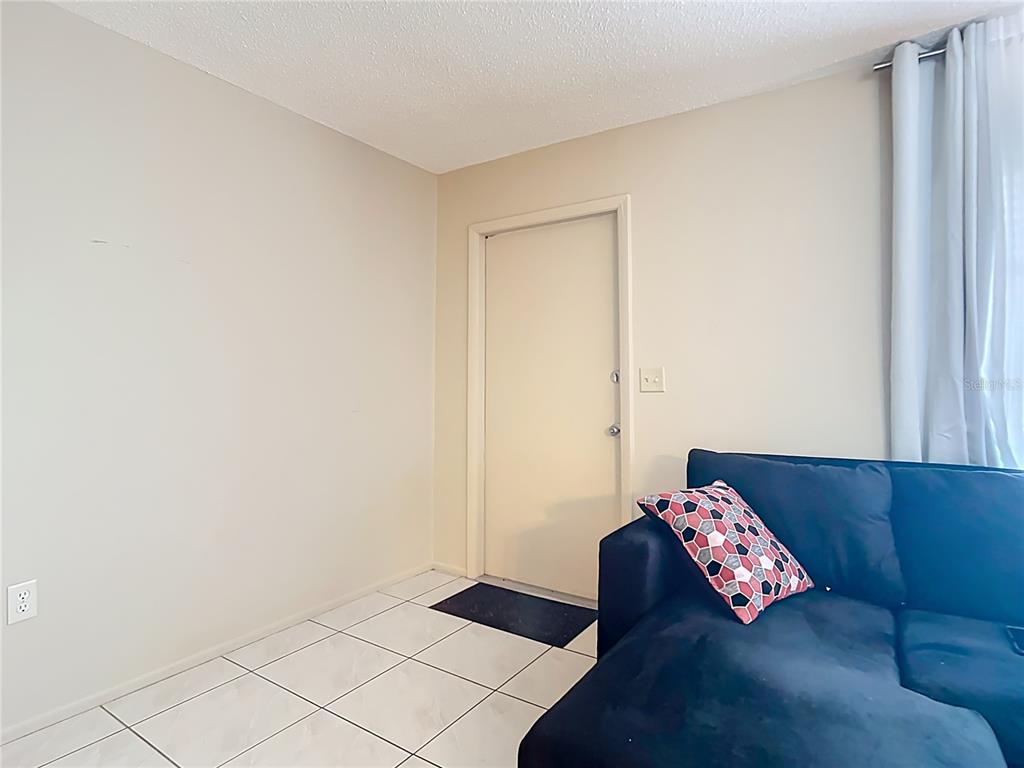 A living room features white tile flooring, a beige wall, and a dark blue sofa — 5964 DIANA ROAD, VENICE, FL
