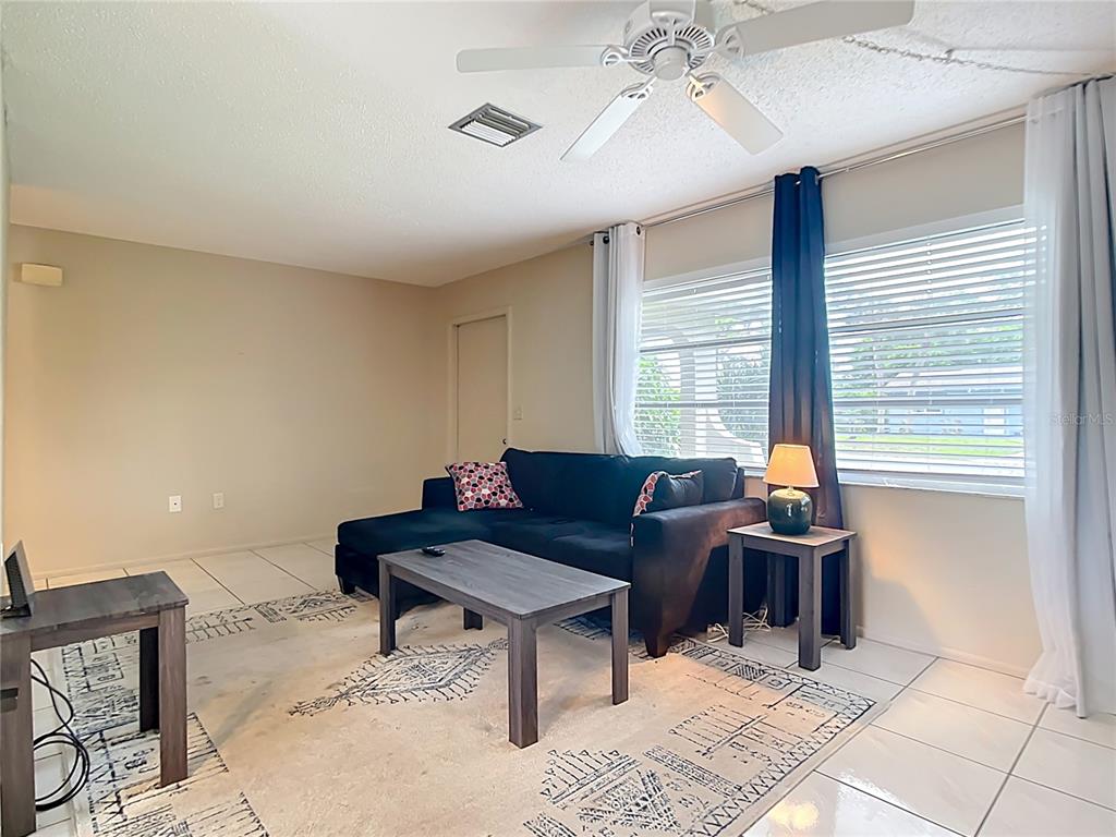 A living room features a black sectional sofa, a coffee table, and tile flooring — 5964 DIANA ROAD, VENICE, FL