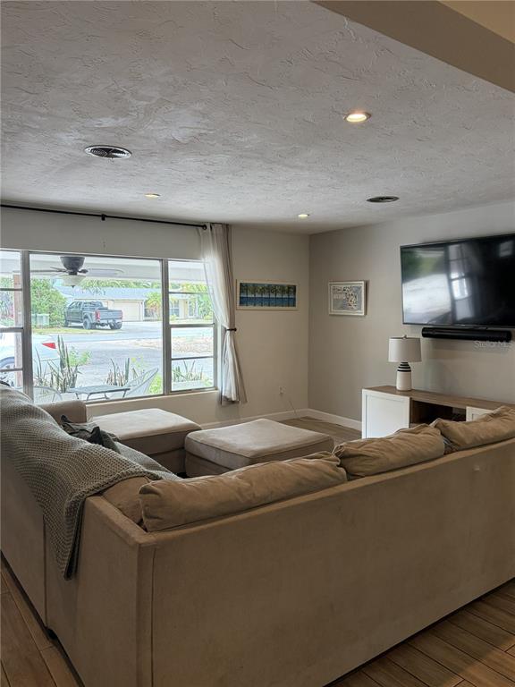 A living room features a large sectional sofa, a television, and a window view — 7503 STARFISH DRIVE, SARASOTA, FL