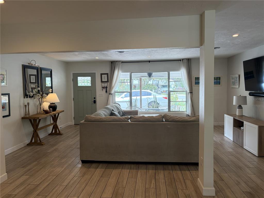 A living room features a beige sofa, wood-look tile flooring, and a large front window — 7503 STARFISH DRIVE, SARASOTA, FL