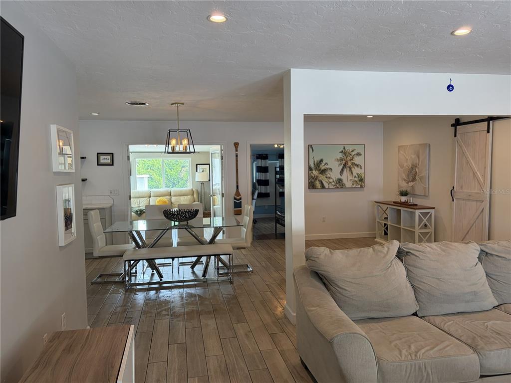 A living room and dining area feature light wood-look tile flooring and white walls — 7503 STARFISH DRIVE, SARASOTA, FL