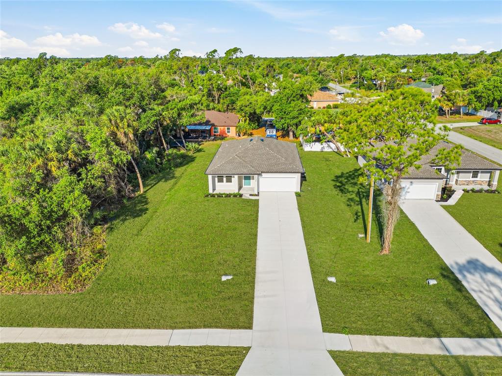 An aerial view shows a single-story house with a long driveway and a large lawn — 5131 S SAN MATEO DRIVE, NORTH PORT, FL