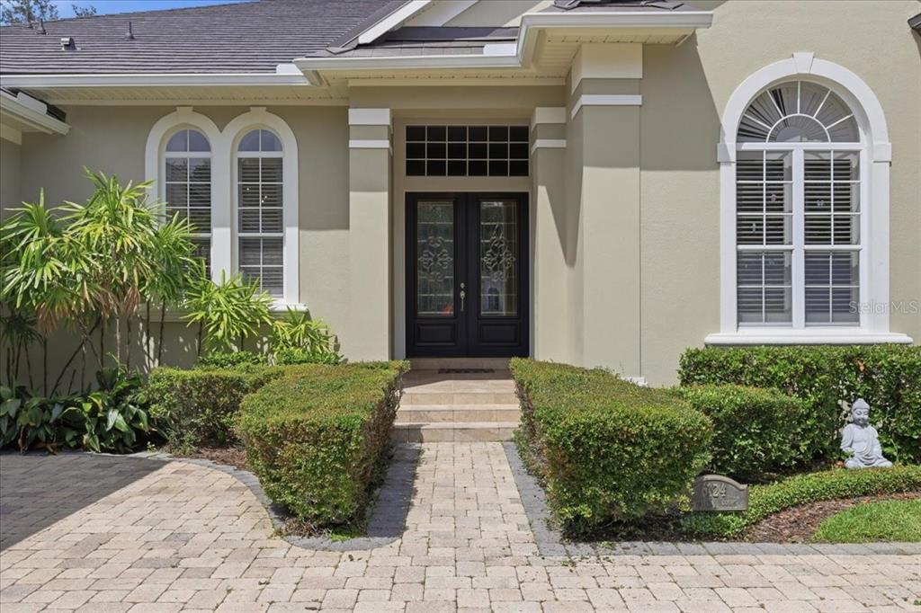 A paved walkway leads to the double front doors of a house with arched windows — 6124 FOXFIELD COURT, WINDERMERE, FL