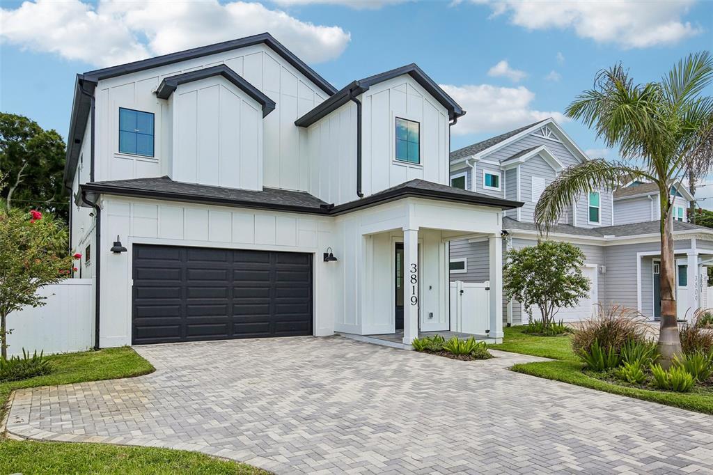 A modern two-story house with white vertical siding, a black garage door, and paver driveway — 3819 71ST STREET N, ST PETERSBURG, FL