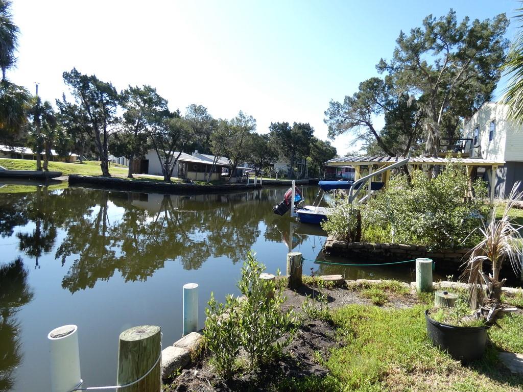 A canal view showing a boat docked at a wooden pier with surrounding trees — 2215 S HUNT POINT, CRYSTAL RIVER, FL