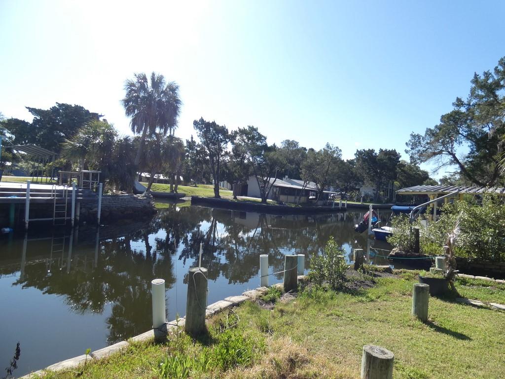 A canal view featuring a wooden dock, boat slip, and surrounding trees under a clear sky — 2215 S HUNT POINT, CRYSTAL RIVER, FL