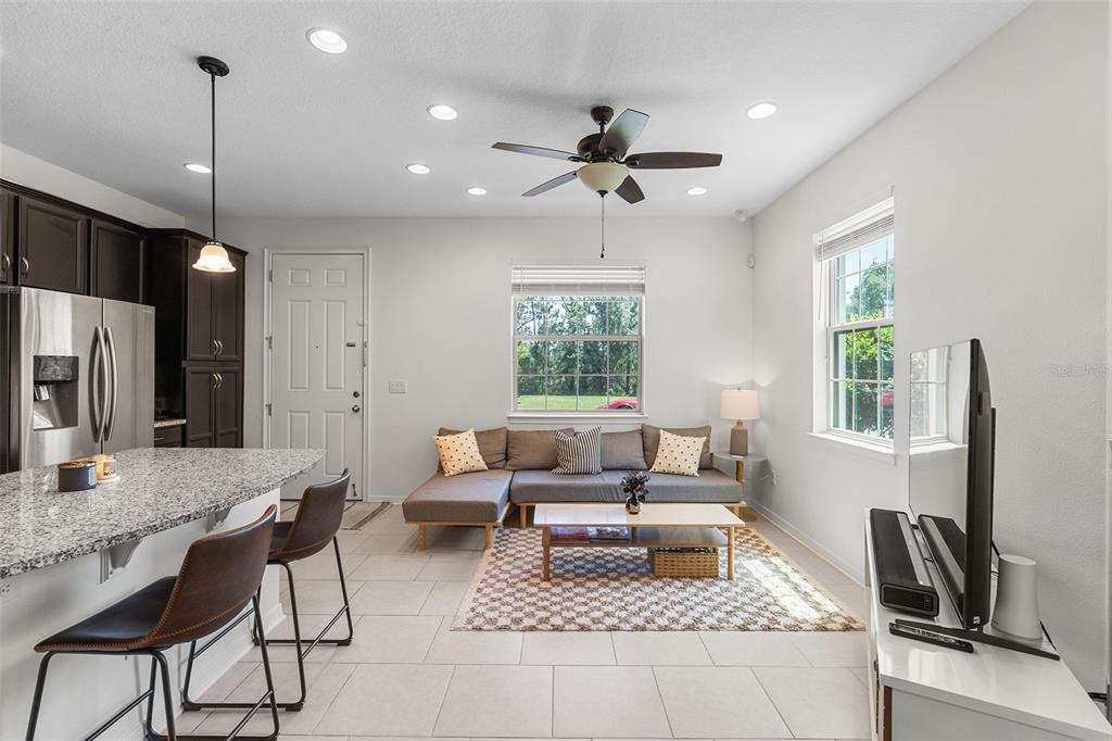 A kitchen with a granite island and stools opens to a living area with a sofa — 14344 SWANLEY STREET, ORLANDO, FL