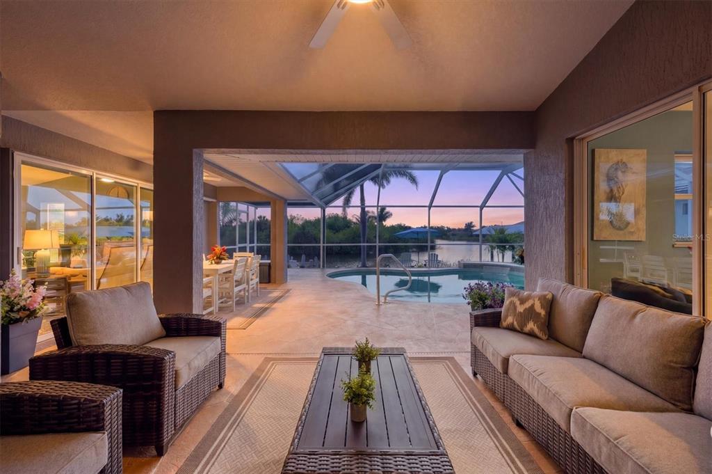 A covered patio features outdoor furniture, a swimming pool, and a view of a lake — 10083 KANSAS CITY STREET, PORT CHARLOTTE, FL