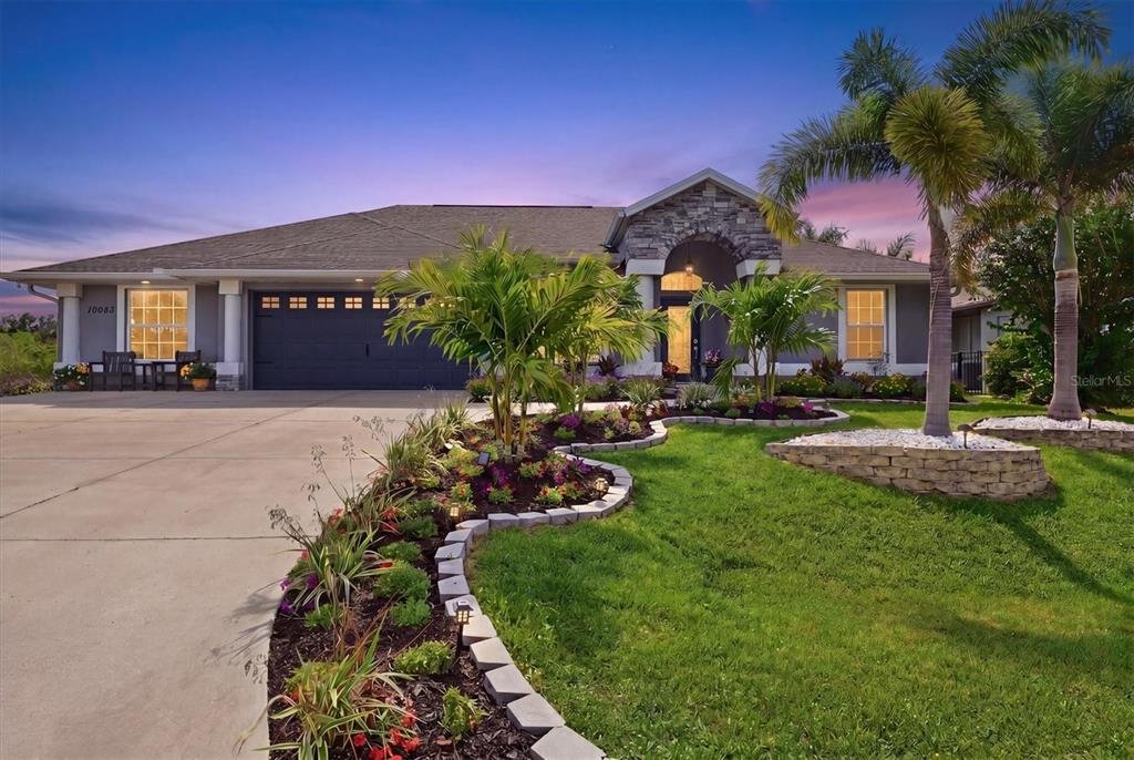 A single-story house with a stone facade, a multi-car garage, and landscaped front yard — 10083 KANSAS CITY STREET, PORT CHARLOTTE, FL