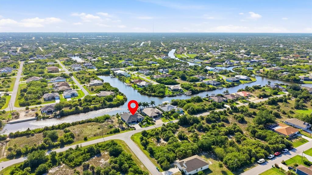 An aerial view shows a house with a red location pin situated along a canal — 10083 KANSAS CITY STREET, PORT CHARLOTTE, FL