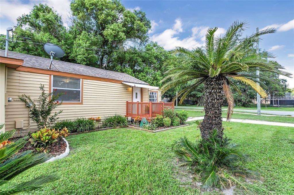 A tan house exterior features a small wooden deck, a palm tree, and landscaping — 2400 SHANNON ROAD, ORLANDO, FL