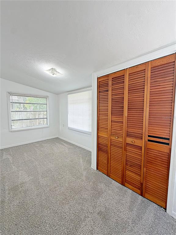 A bedroom features gray carpet, white walls, two windows with blinds, and wooden louvered closet doors — 2400 SHANNON ROAD, ORLANDO, FL
