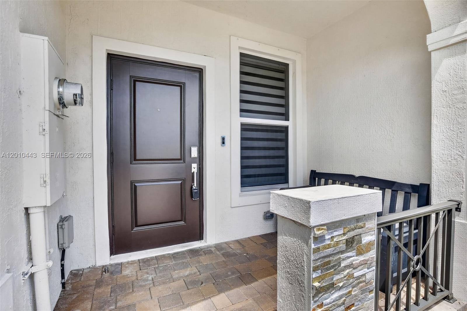 A dark brown front door sits next to a window on a paved porch — 2691 NW 55th Way, Lauderhill FL 33313, LAUDERHILL, FL