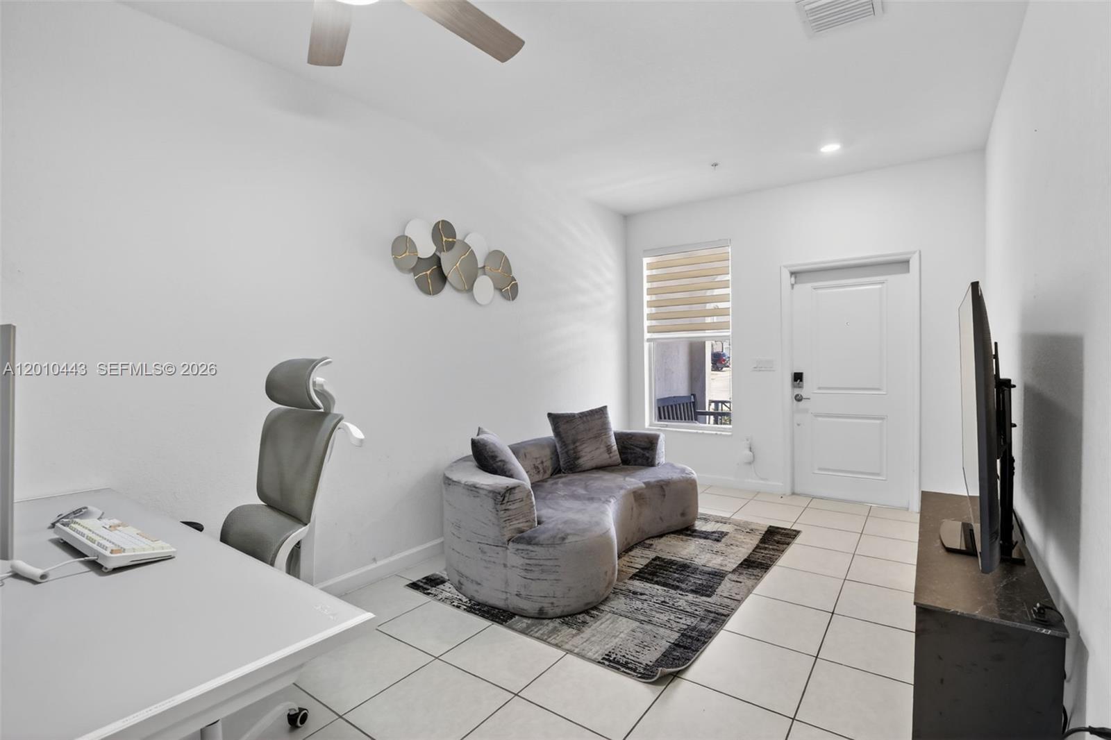 A room with white walls, tile flooring, a desk, a curved sofa, and a television — 2691 NW 55th Way, Lauderhill FL 33313, LAUDERHILL, FL
