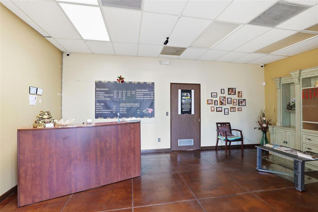 A reception area features a wooden desk, a service menu, and a waiting chair — 0000 WICKHAM RD, MELBOURNE, FL