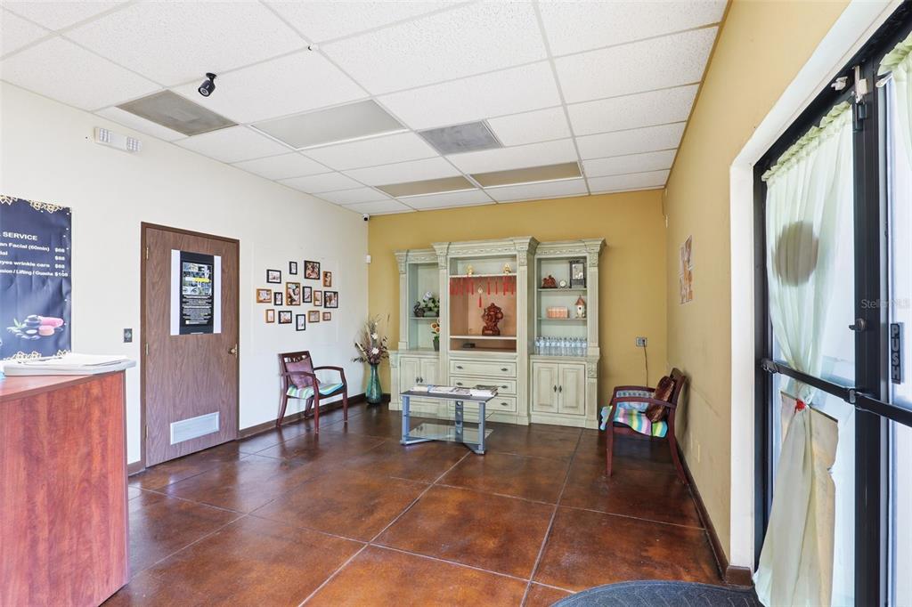 A waiting area features tile flooring, a light-colored hutch, and two chairs against yellow walls — 0000 WICKHAM RD, MELBOURNE, FL