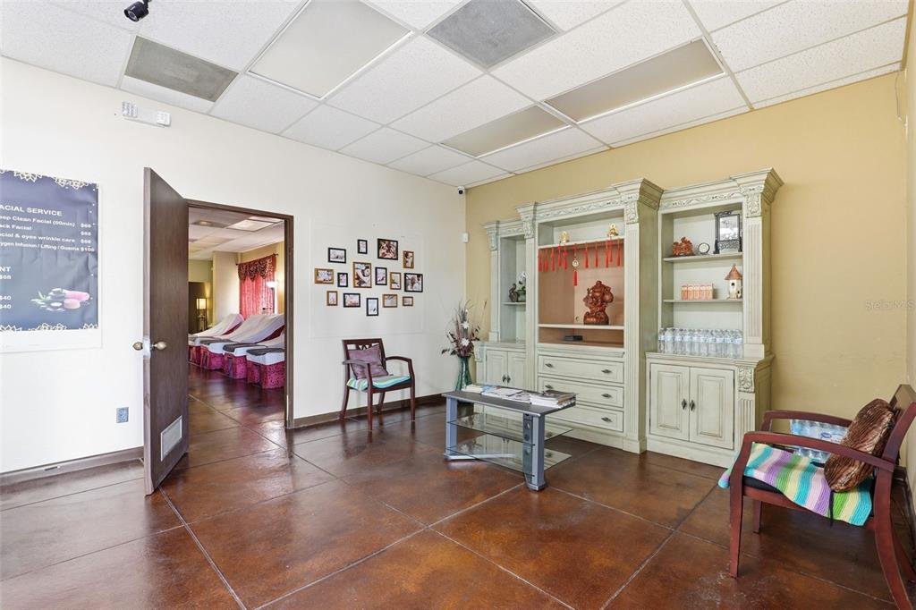 A waiting room features a tiled floor, a gallery wall, a hutch, and two chairs — 0000 WICKHAM RD, MELBOURNE, FL