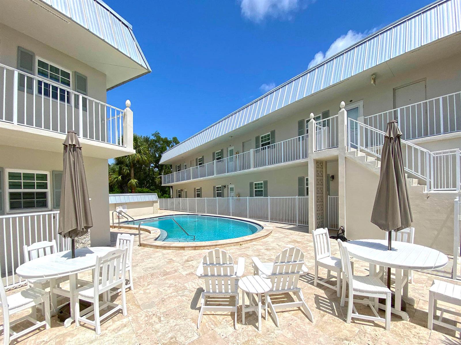 A swimming pool sits in the courtyard of a two-story apartment building with balconies — 900 Jasmine Lane # 9a, Vero Beach FL 32963, VERO BEACH, FL