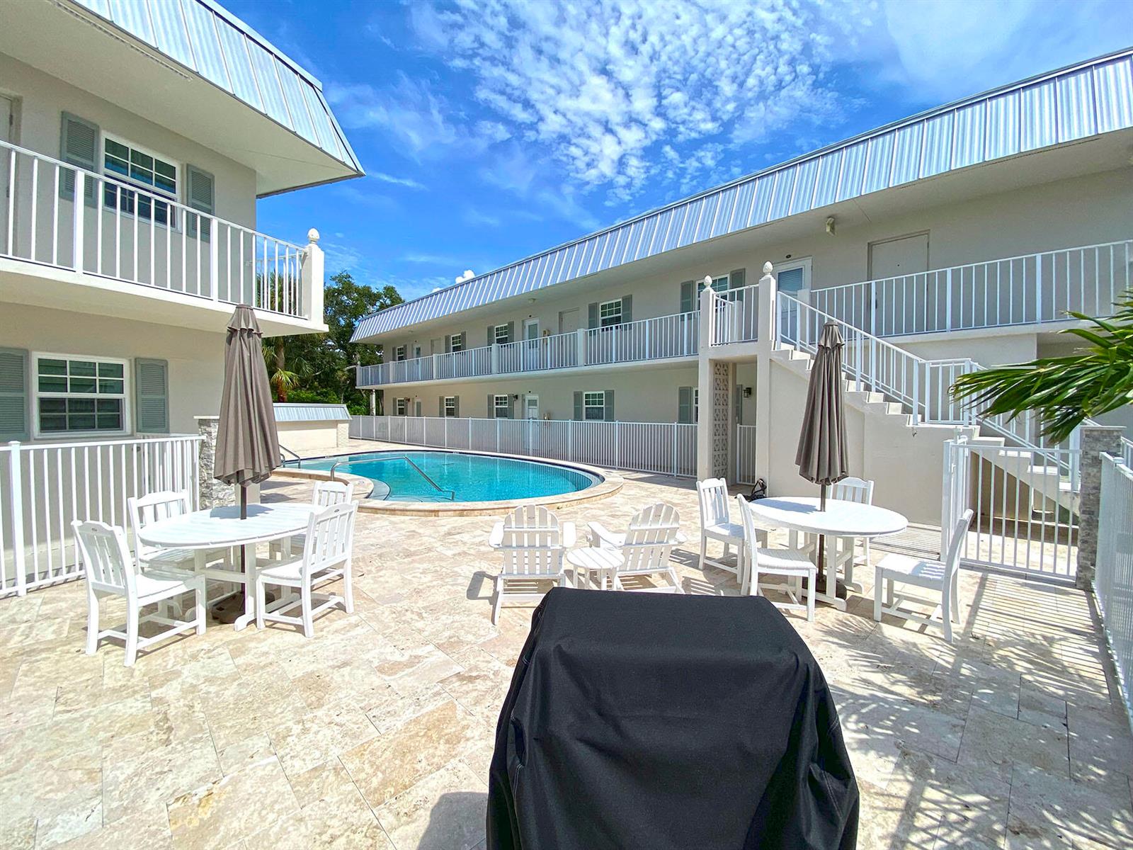 A pool area with patio furniture and a covered grill sits between two apartment buildings — 900 Jasmine Lane # 9a, Vero Beach FL 32963, VERO BEACH, FL